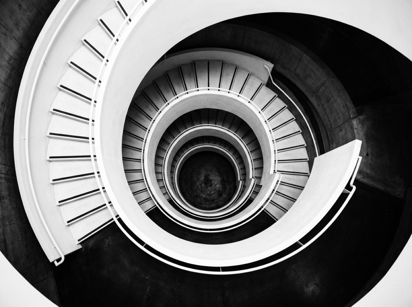 Black and white view down a spiral concrete staircase